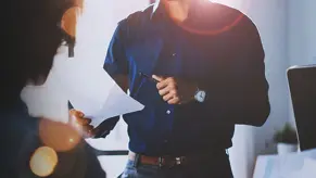 Young team of coworkers making great meeting discussion in modern coworking office.Hispanic businessman talking with two beautiful womans.Teamwork process.Horizontal,blurred background,sun effect